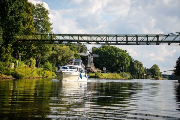 Sportboot unterwegs auf dem Dortmund-Ems-Kanal in Meppen, im Hintergrund ist die Höltingmühle zu sehen