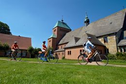 Radfahrer unterwegs auf der Pionierroute vor der Kirche St. Johannes Apostel in Wietmarschen 